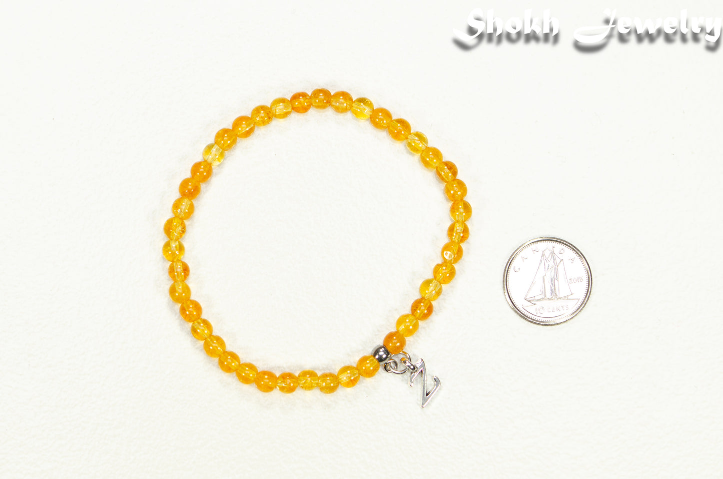 4mm Citrine Bracelet with Initial beside a dime.