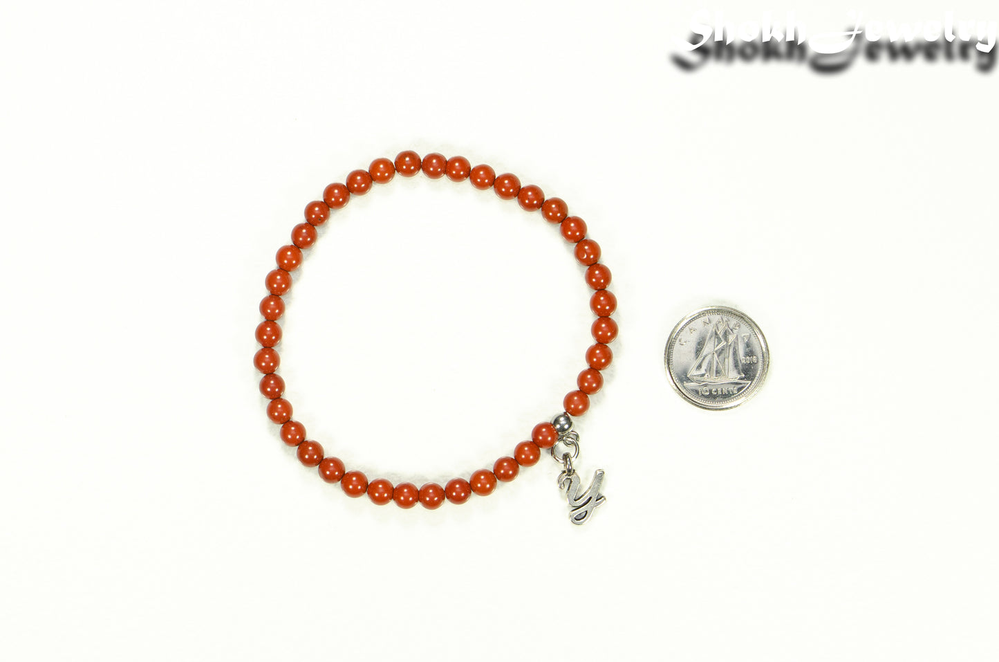 4mm Red Jasper Bracelet with Initial beside a dime.