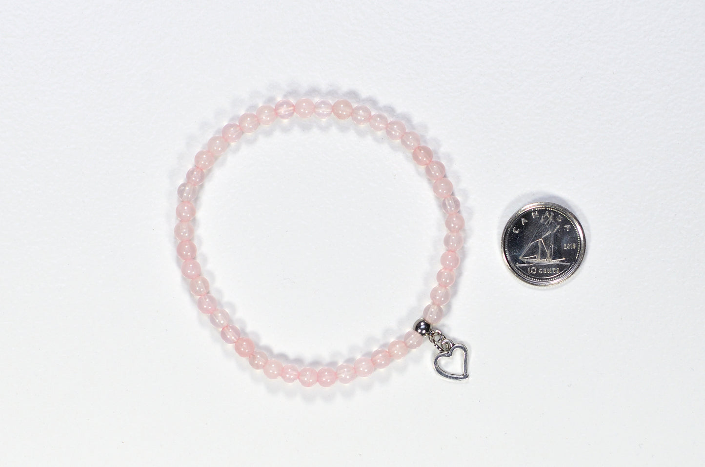 4mm Rose Quartz Bracelet with Heart Charm beside a dime.