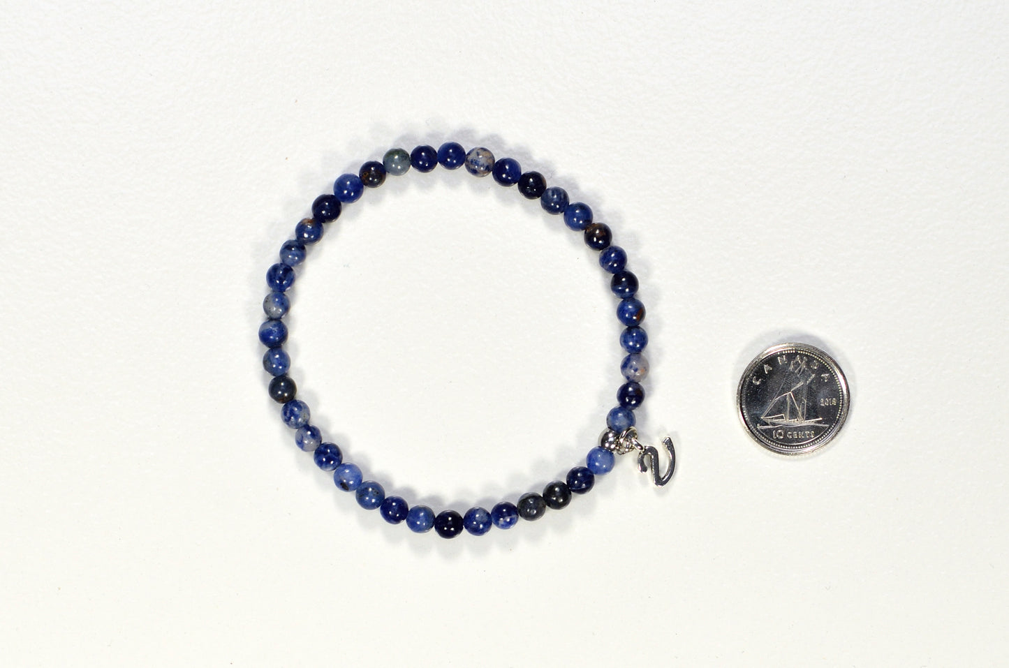 4mm Sodalite Bracelet with Initial beside a dime.