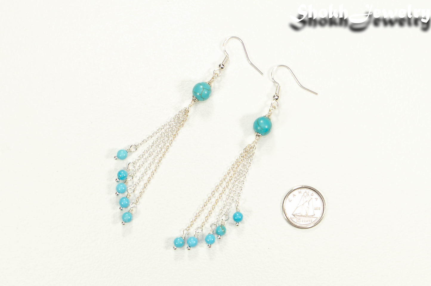 Cascading Turquoise Howlite Gemstone Drop Earrings beside a dime.