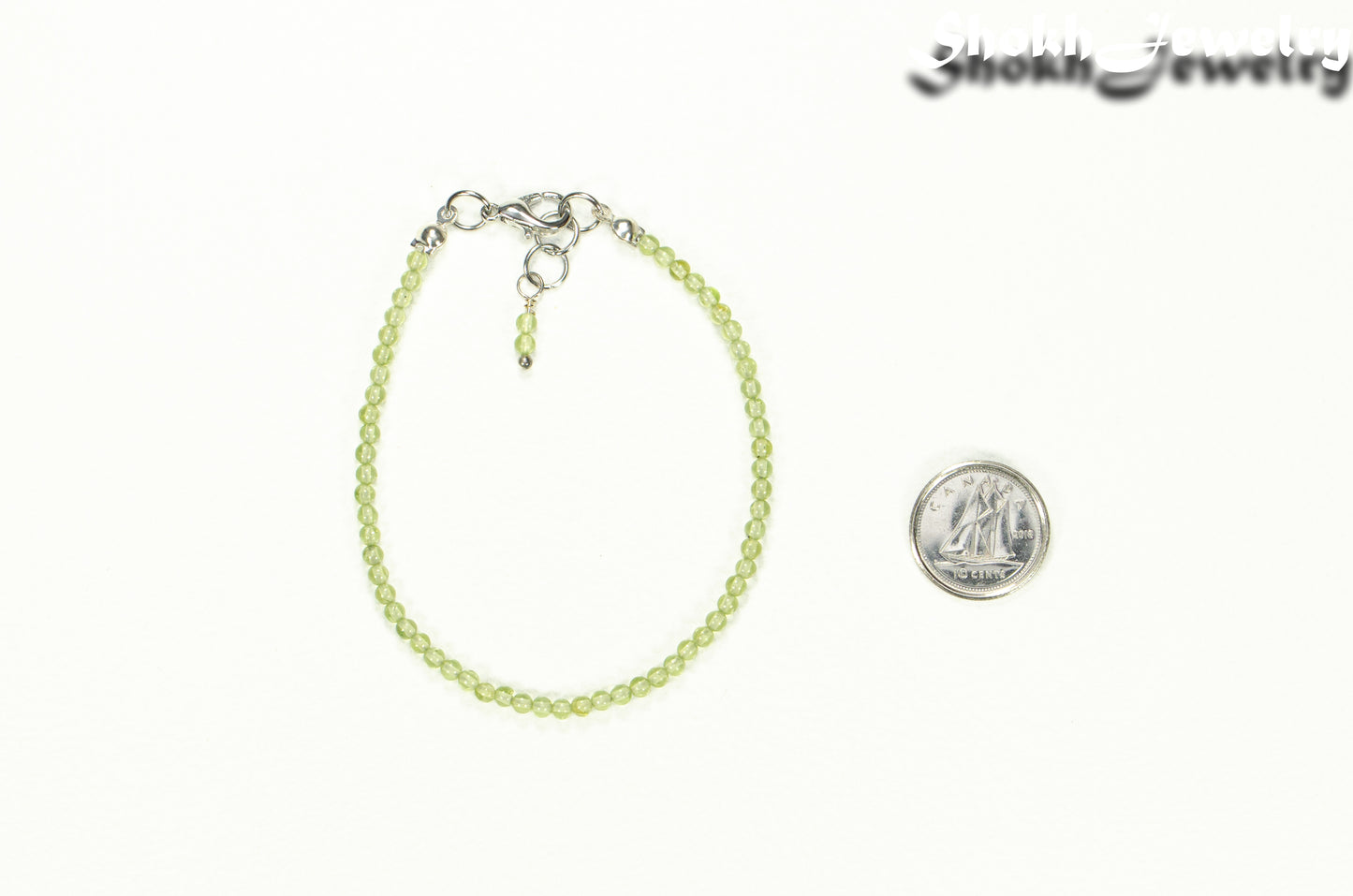 Dainty Peridot anklet beside a dime.