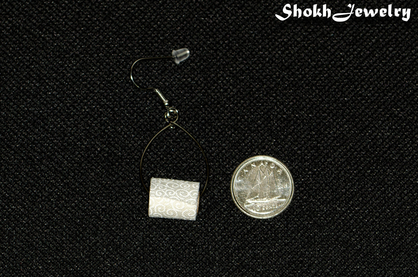 Tiny Toilet Paper Roll Earring beside a dime.