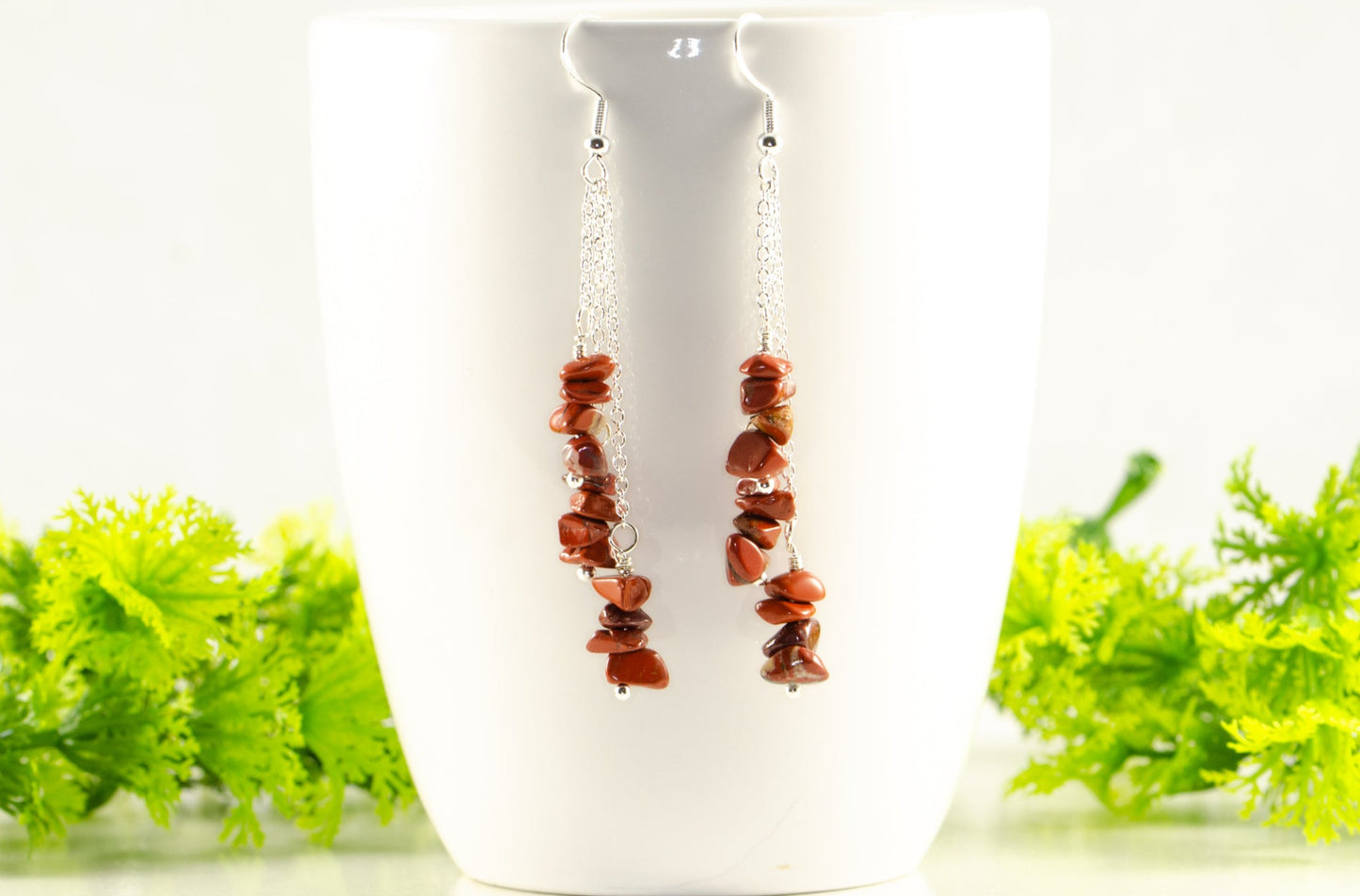 Long Silver Plated Chain and Red Jasper Chip Earrings displayed on a coffee mug.