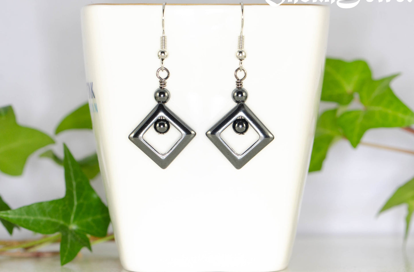 Small Black Hematite Geometric Earrings displayed on a tea cup.