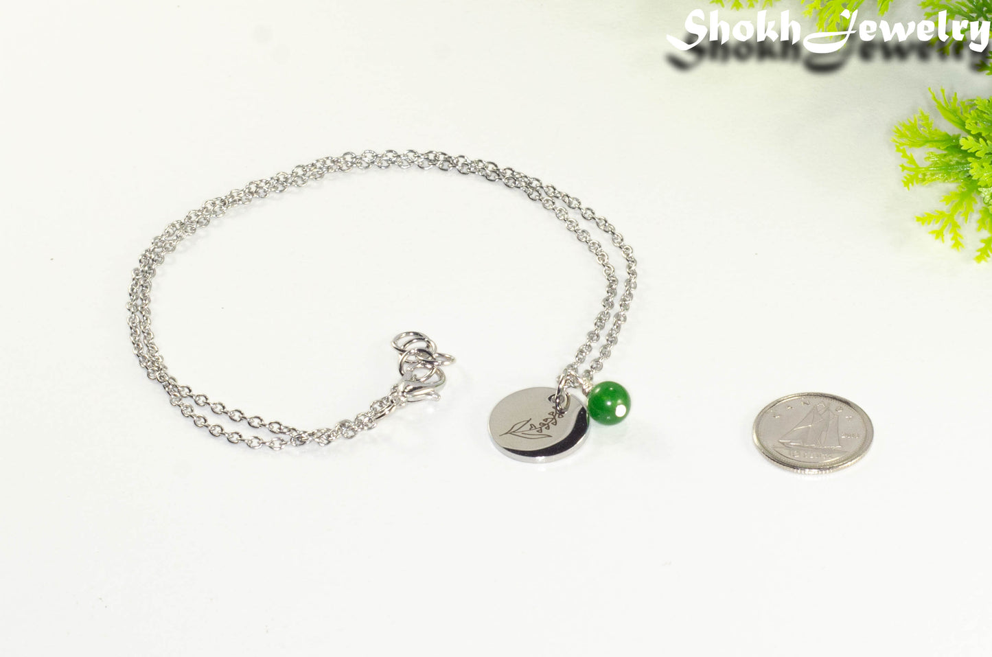 May Birth Flower Necklace with Emerald Birthstone Pendant beside a dime.