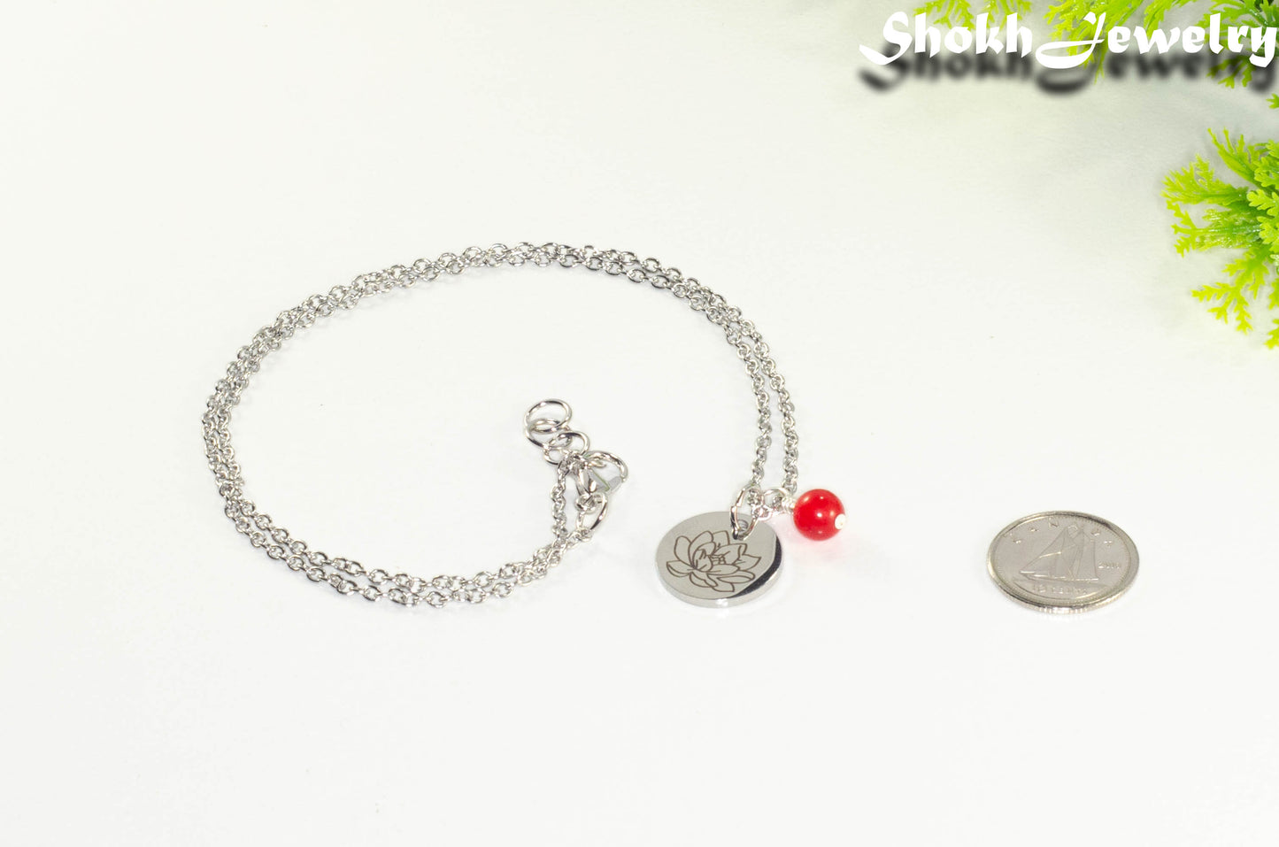 July Birth Flower Necklace with Red Ruby Birthstone Pendant beside a dime.