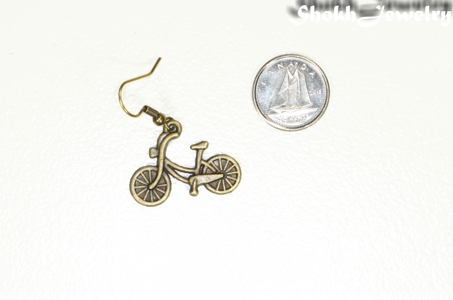 Antique Bronze Bicycle Charm Earrings beside a dime.