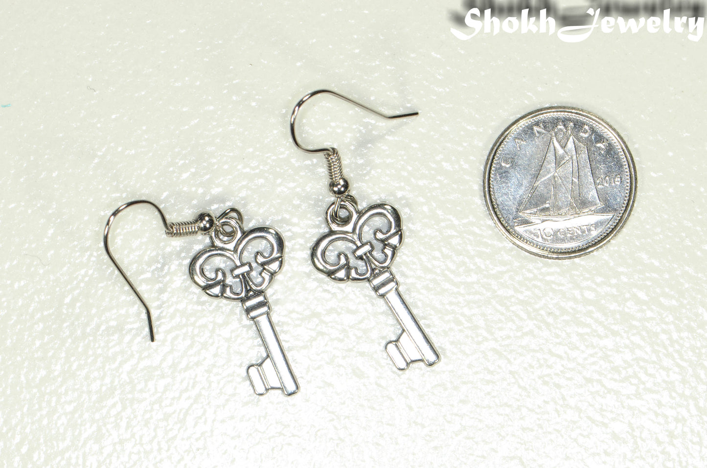 Small Skeleton Key Charm Earrings beside a dime.