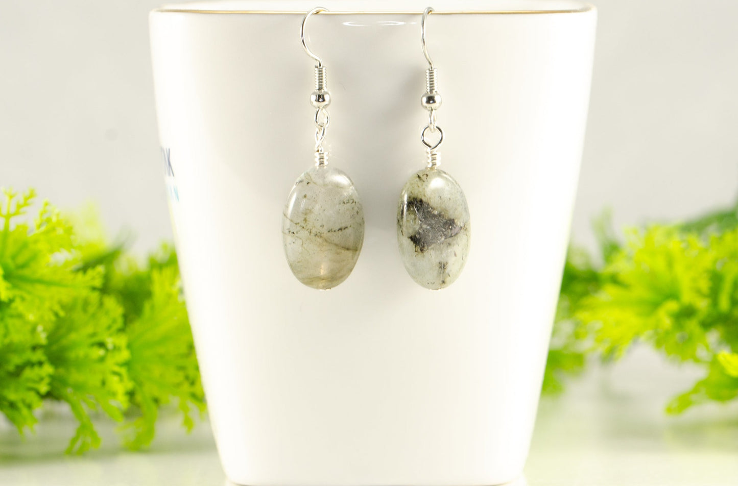 Natural Labradorite Crystal Earrings displayed on a tea cup.
