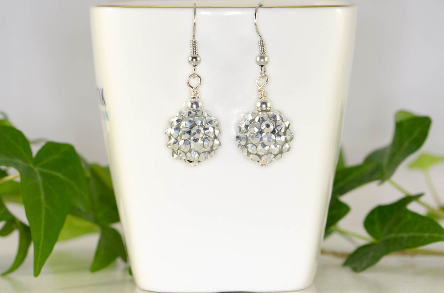 14mm Rhinestone Disco Ball Earrings displayed on a tea cup.