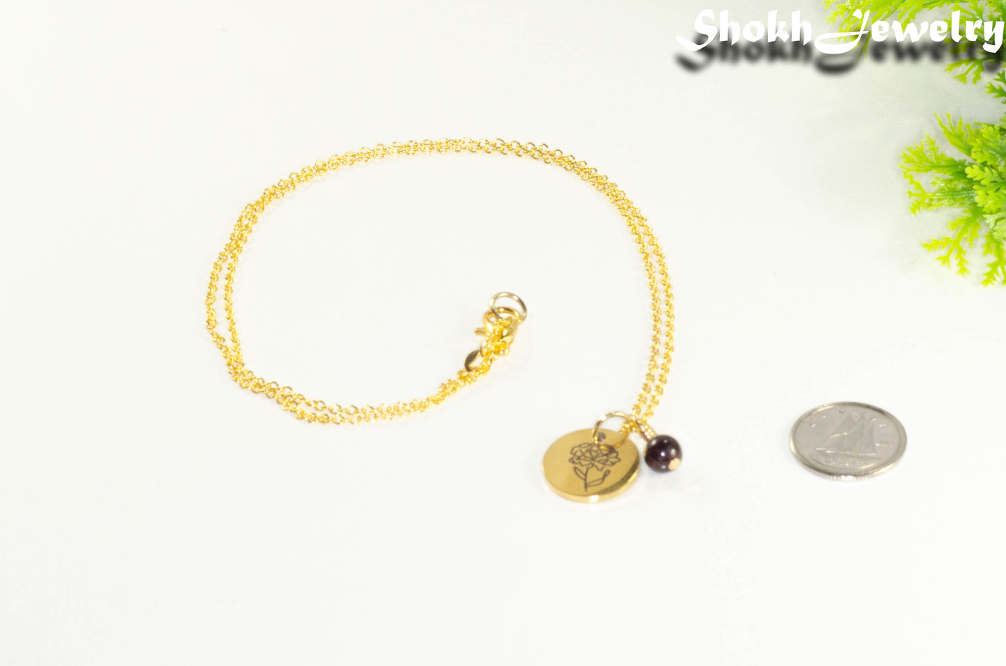 Gold Plated January Birth Flower Necklace with Garnet Birthstone Pendant beside a dime.