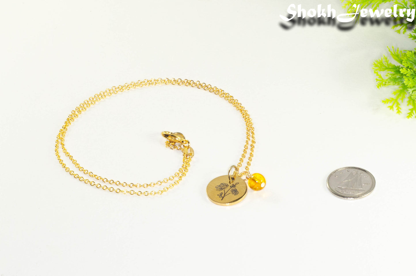 Gold Plated November Birth Flower Necklace with Citrine Birthstone Pendant beside a dime.