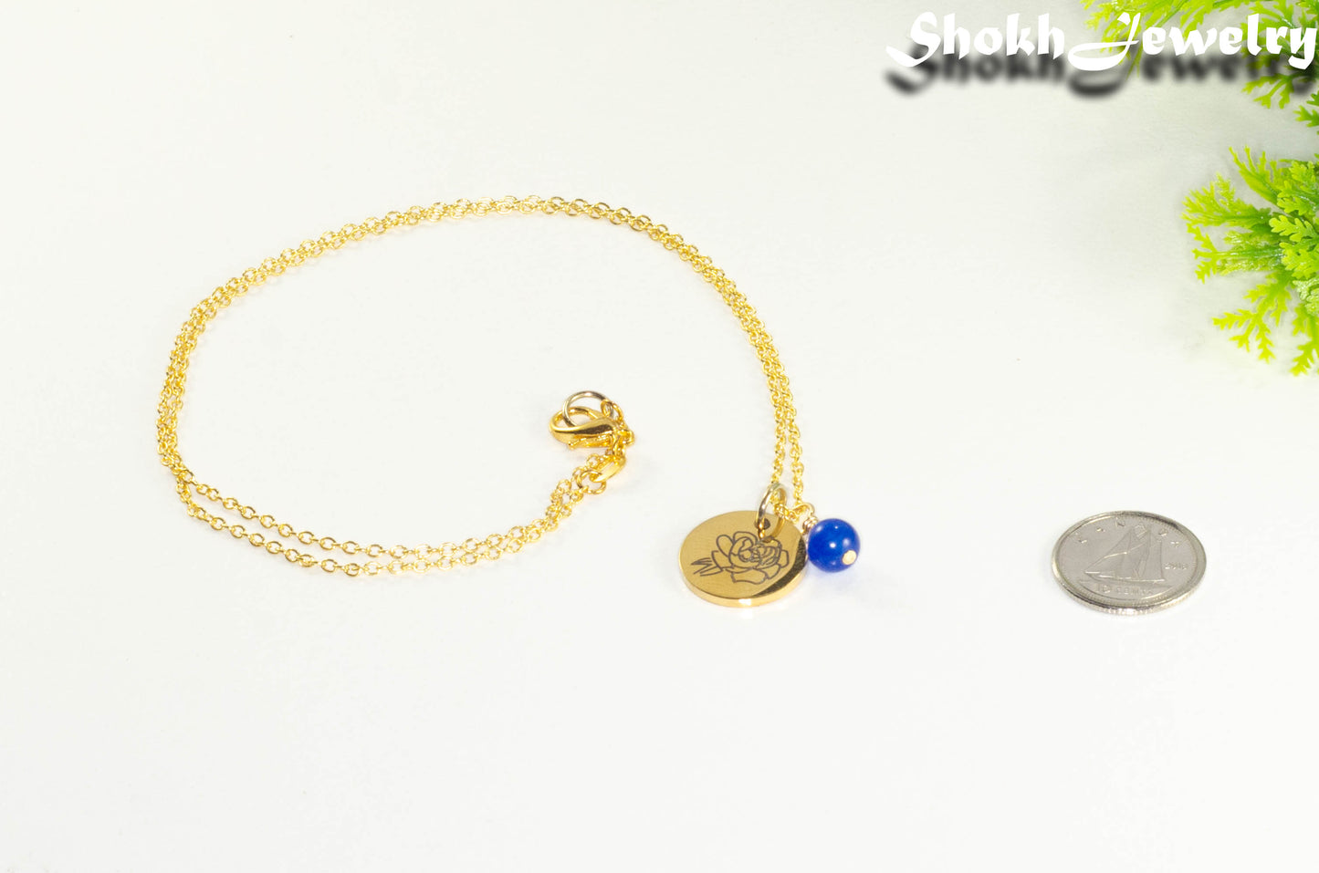 Gold Plated September Birth Flower Necklace with Sapphire Birthstone Pendant beside a dime.