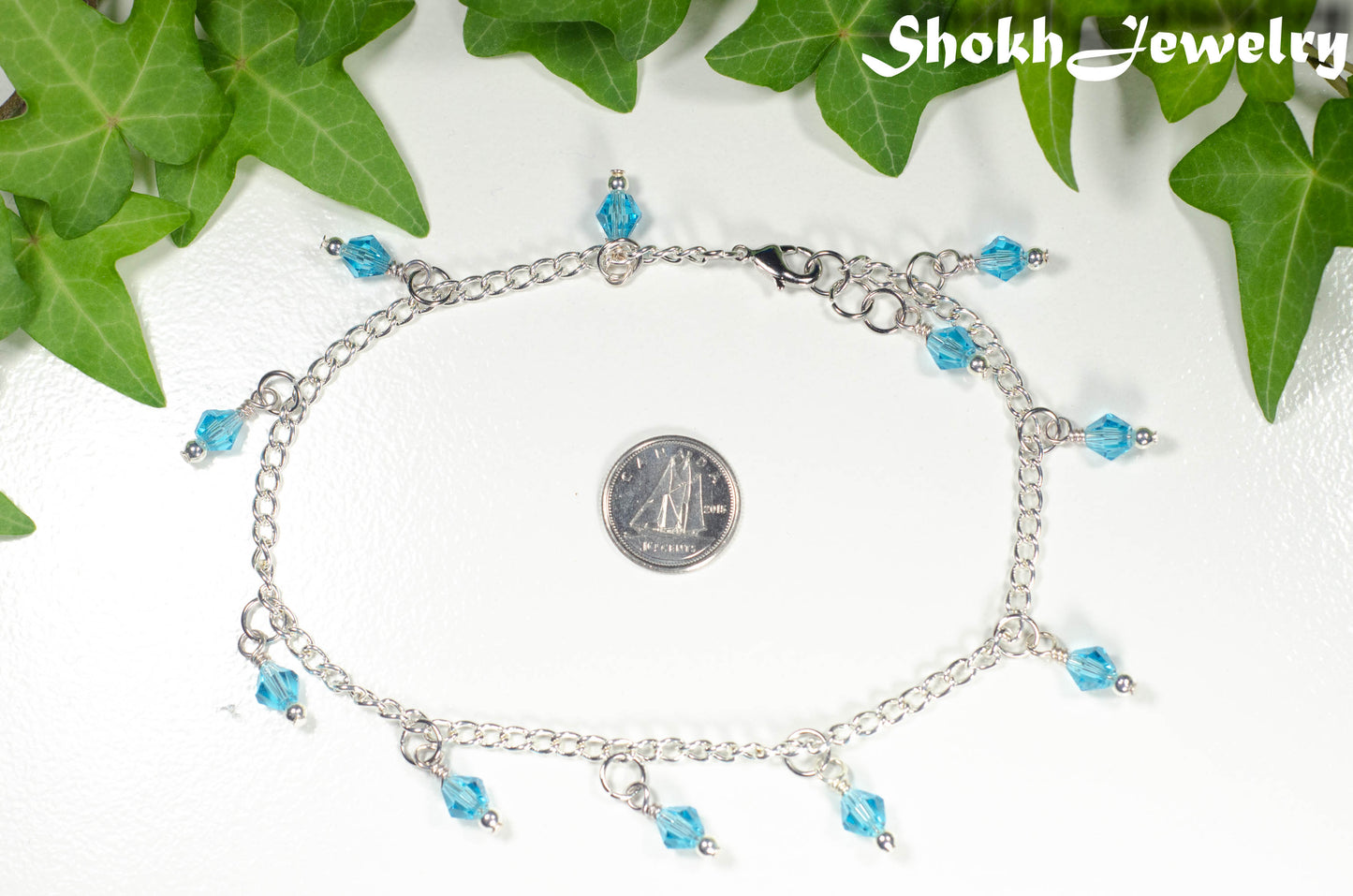 Aqua Blue Glass Crystal Dangle and Chain Anklet beside a dime.