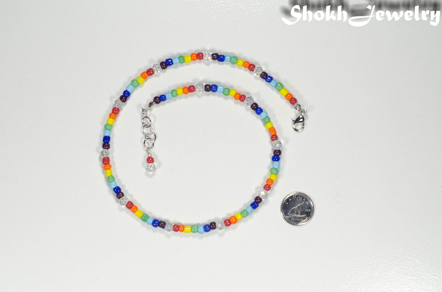 Clear Glass Crystal and Rainbow Seed Bead Choker Necklace beside a dime.