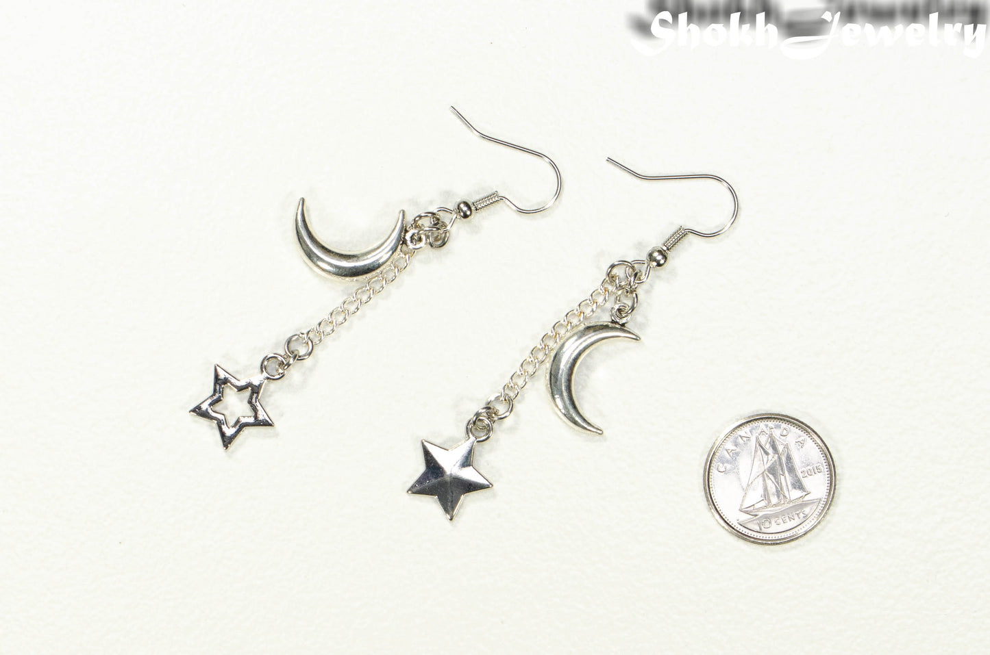 Crescent Moon and Mismatched Star Earrings beside a dime.