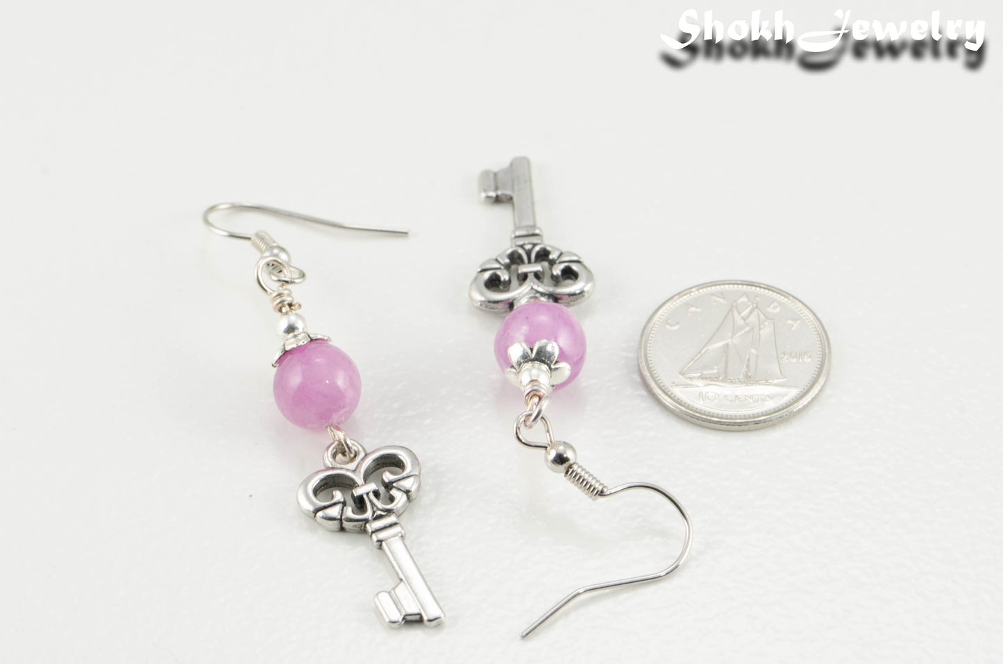 Light Purple Quartzite and Key Charm Dangle Earrings beside a dime.