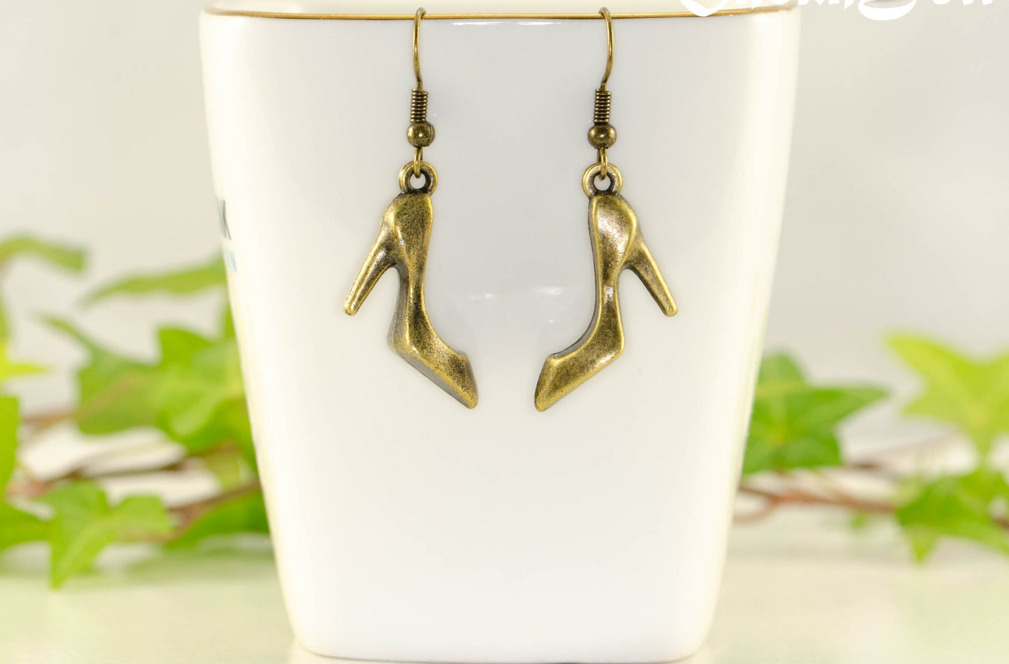Antique Bronze High Heel Shoe Charm Earrings displayed on a tea cup.
