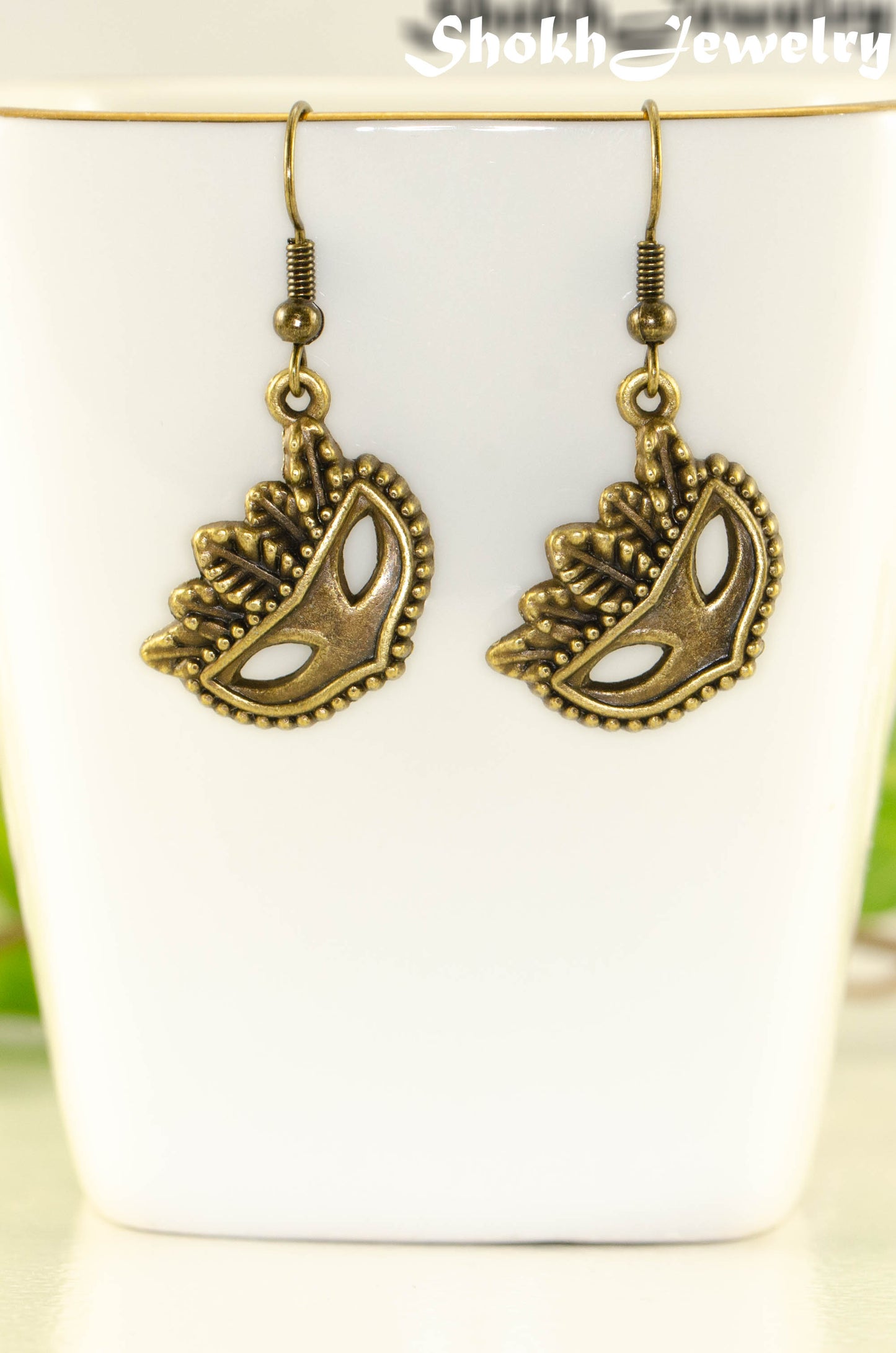 Close up of Antique Bronze Masquerade Mask Charm Earrings.