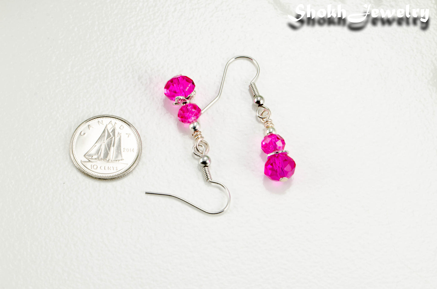 Small Hot Pink Glass Bead Dangle Earrings beside a dime.
