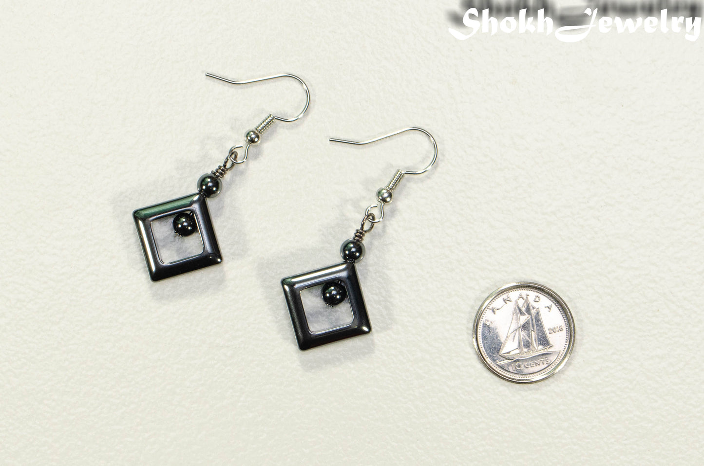 Small Black Hematite Geometric Earrings beside a dime.
