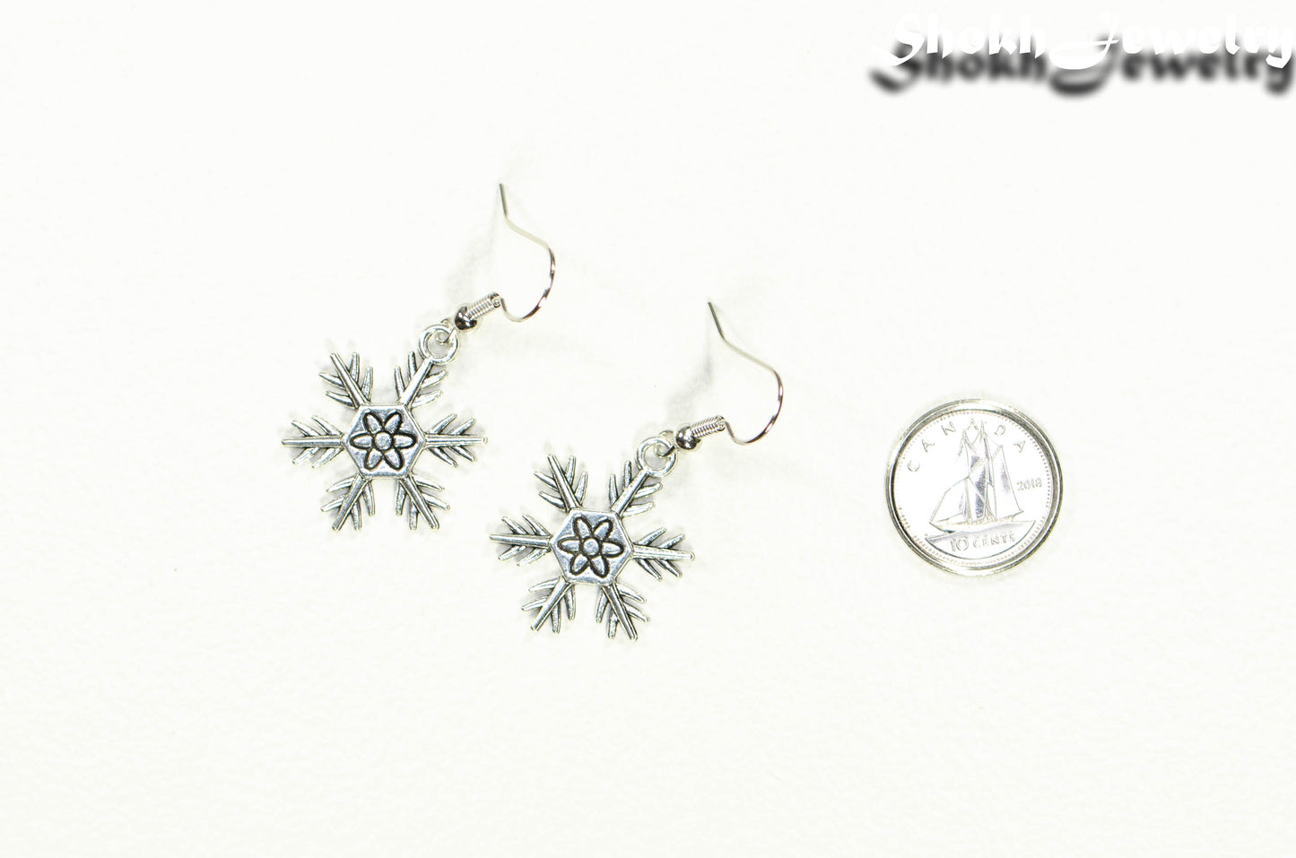 Christmas Snowflakes Charm Earrings beside a dime.