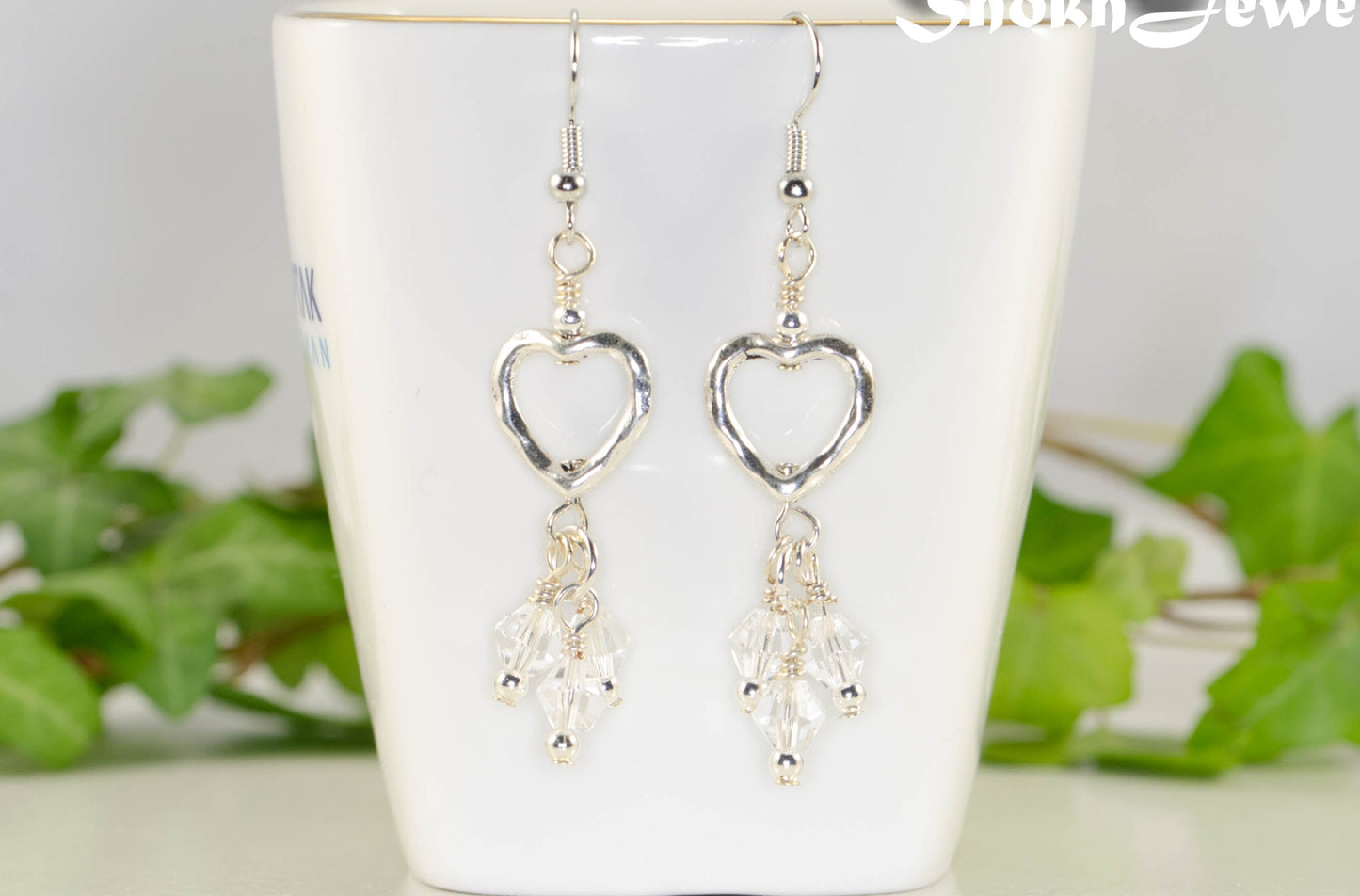 Silver Plated Heart and Clear Glass Crystal Cluster Earrings displayed on a tea cup.