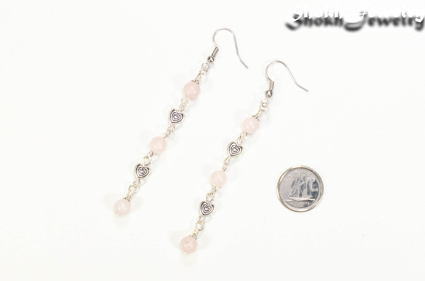 Long Rose Quartz and Heart Earrings beside a dime.