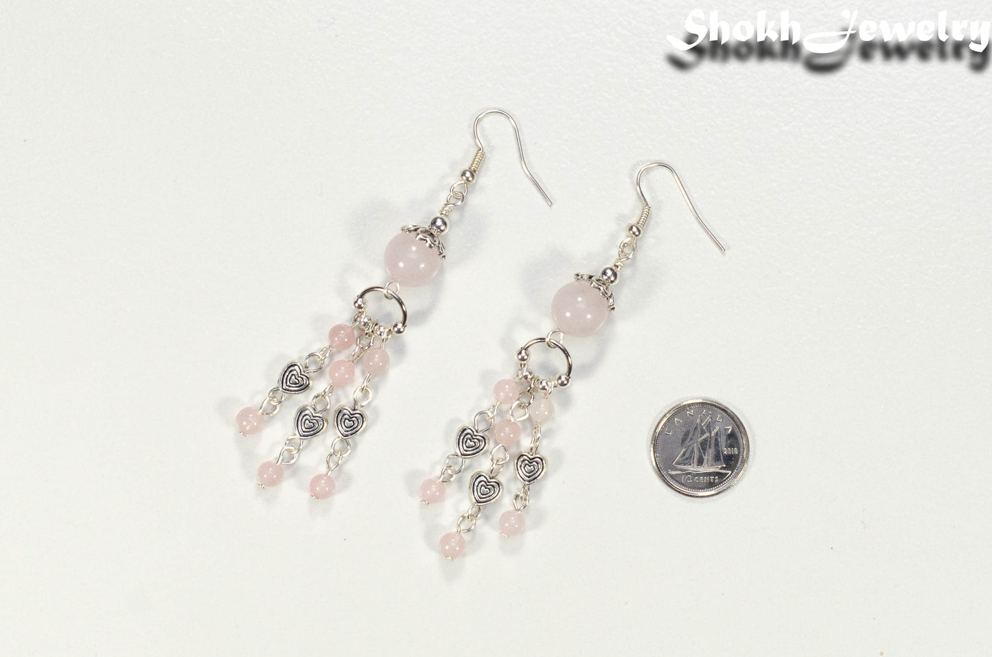 Statement Rose Quartz and Heart Chandelier Earrings beside a dime.