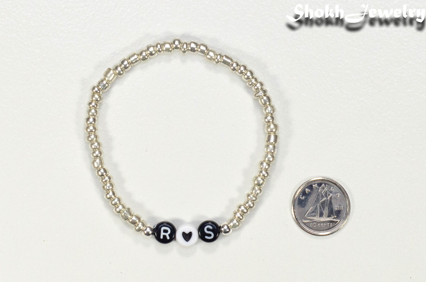 Silver Seed Beads Bracelet with Initials beside a dime.