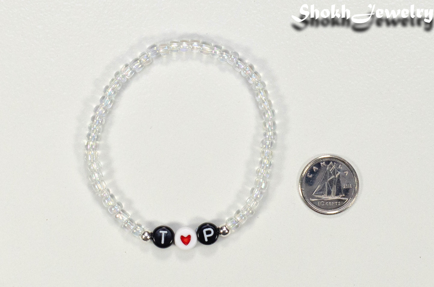 Clear Seed Beads Bracelet with Initials beside a dime.