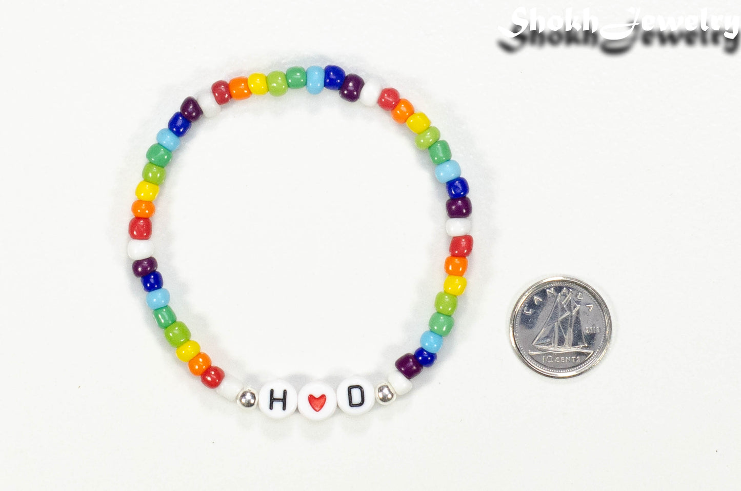 Rainbow seed beads Bracelet with Initials beside a dime.