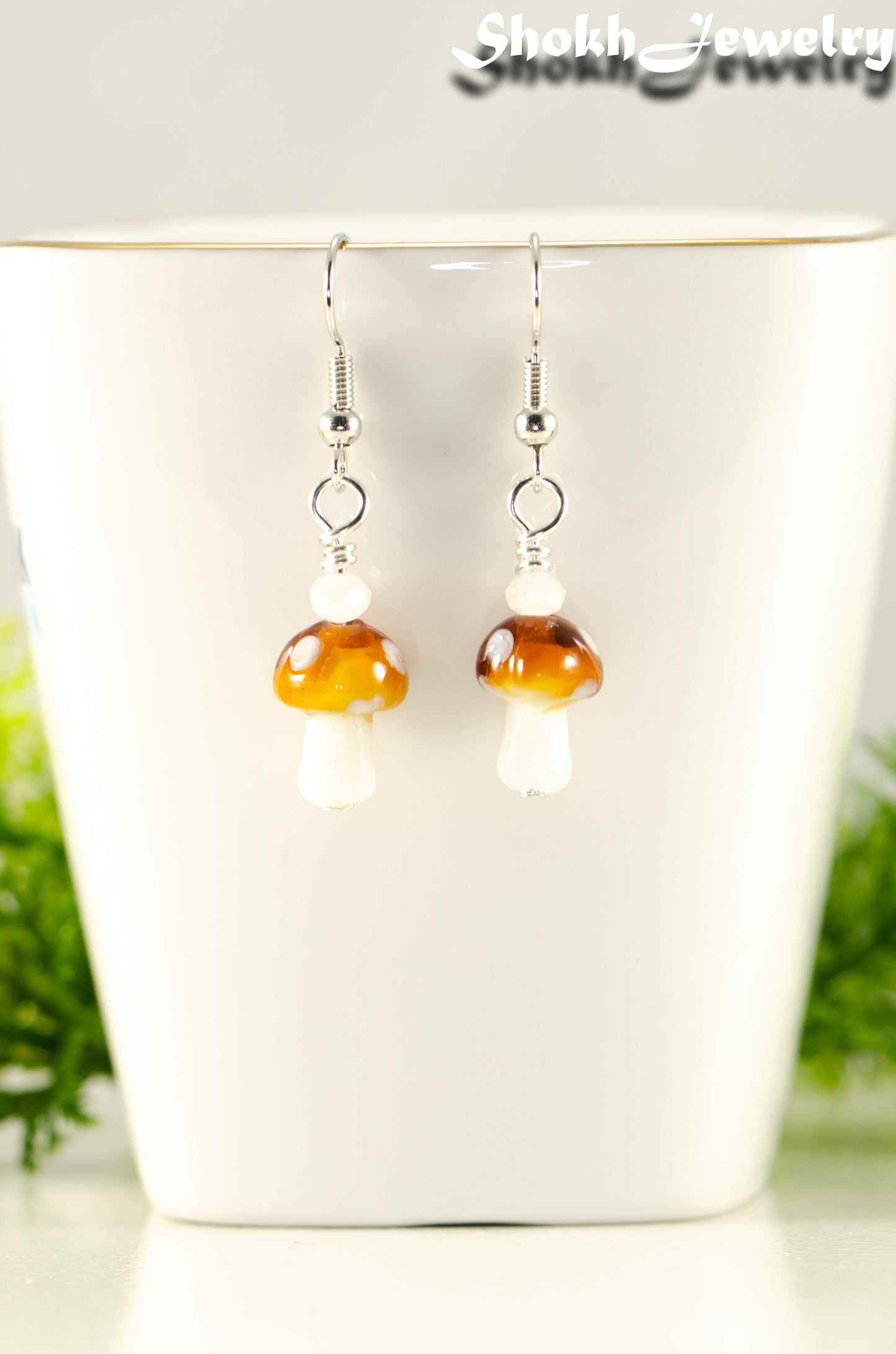 Close up of Tiny Brown Mushroom Glass Bead Earrings.