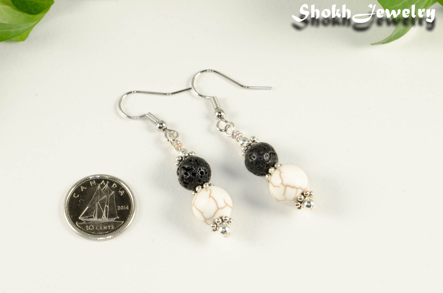 White Howlite and Black Lava Rock Earrings beside a dime.