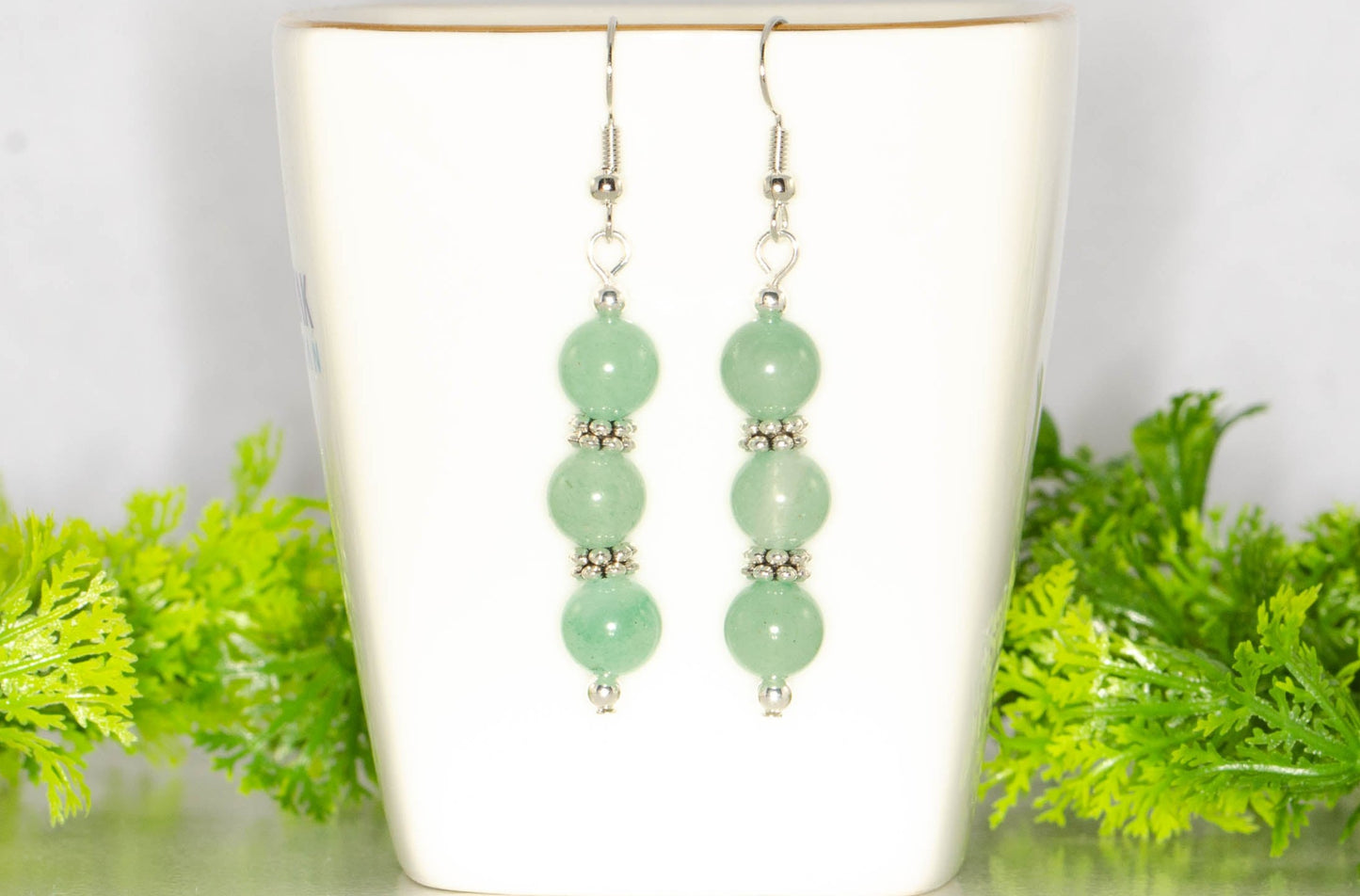 Natural Green Aventurine Beaded Bar Earrings displayed on a tea cup.