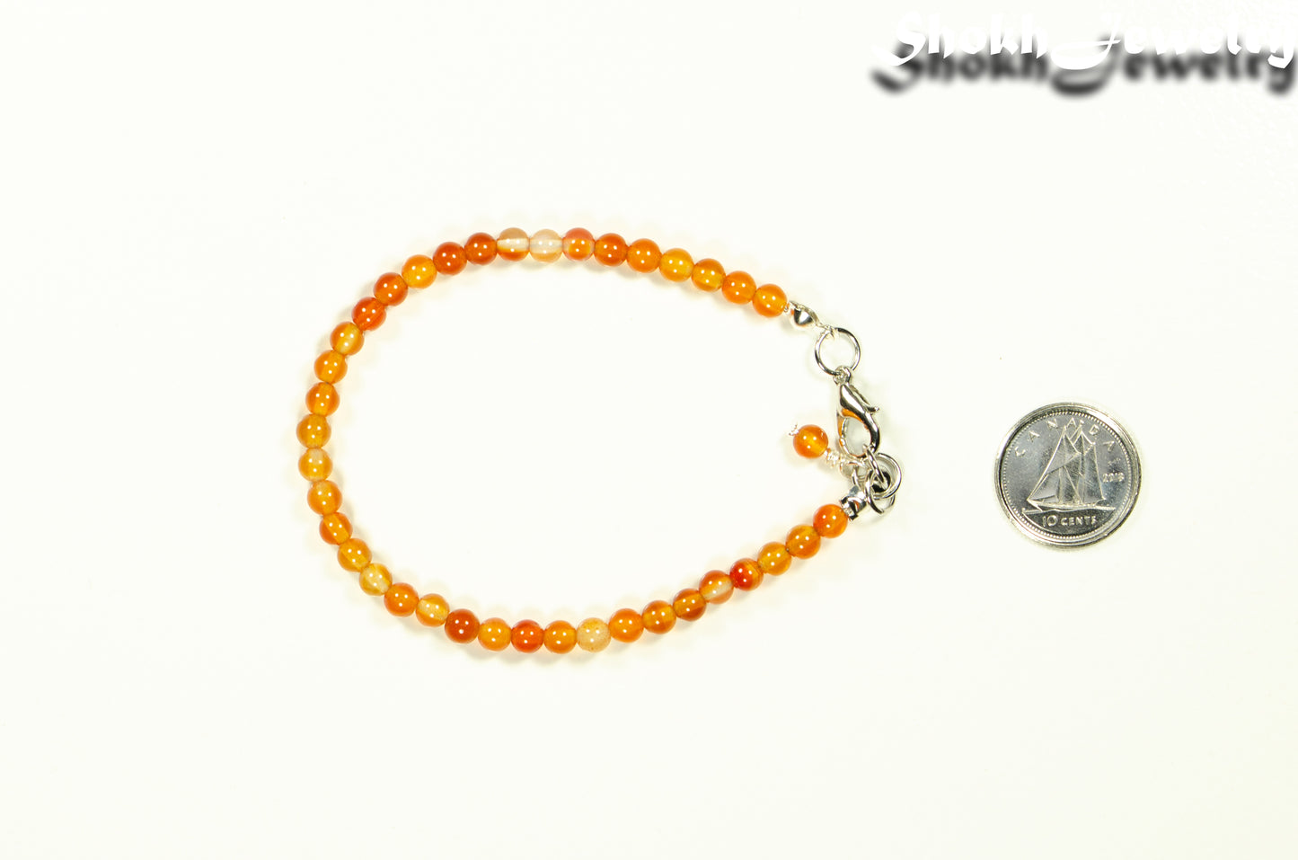4mm Carnelian Crystal Bracelet with Clasp beside a dime.