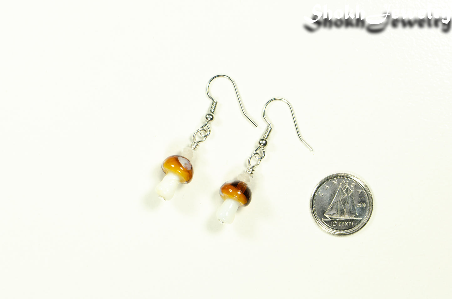 Tiny Brown Mushroom Glass Bead Earrings beside a dime.