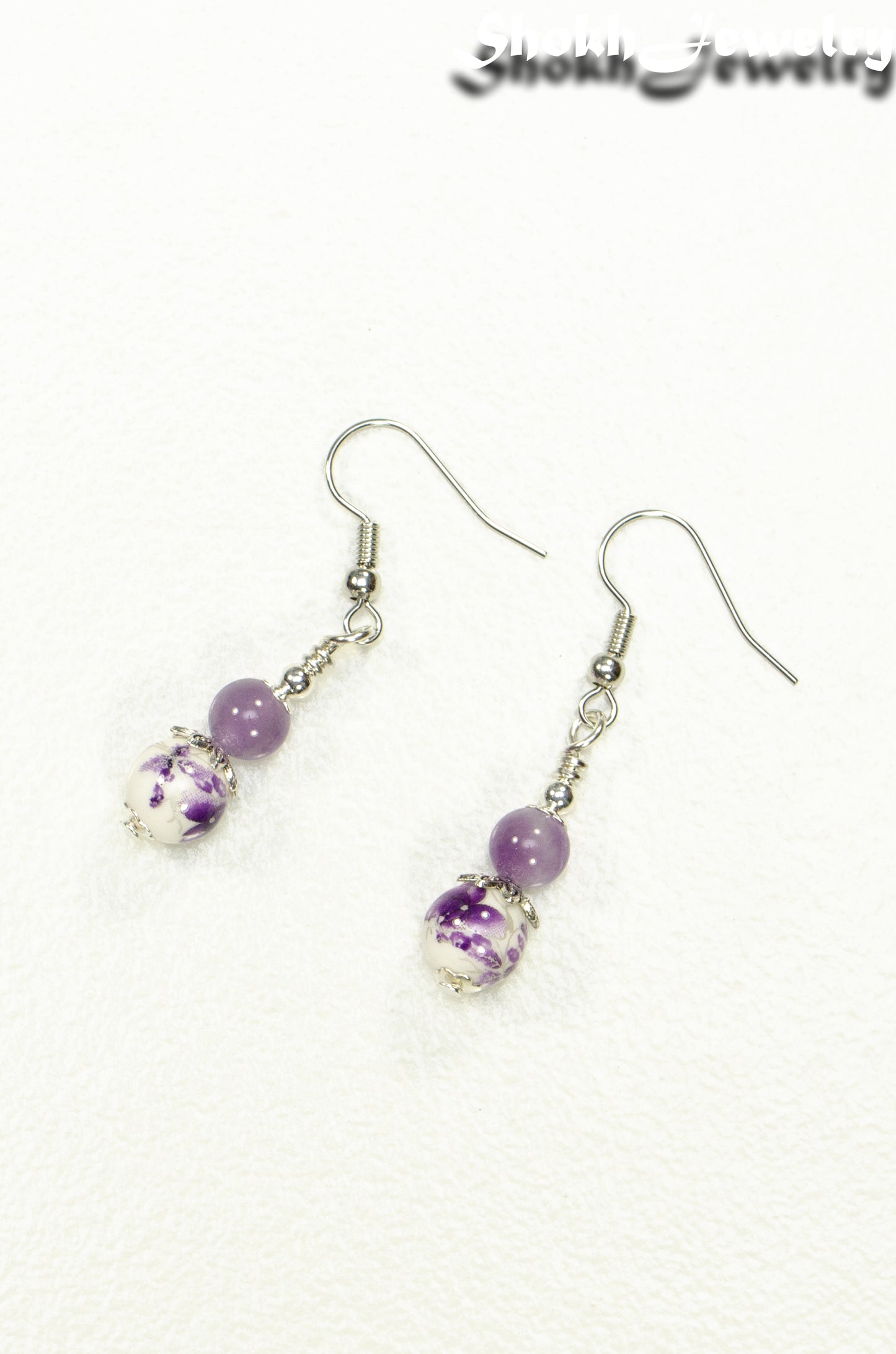 Top view of Small Floral Ceramic Bead and Amethyst Earrings.