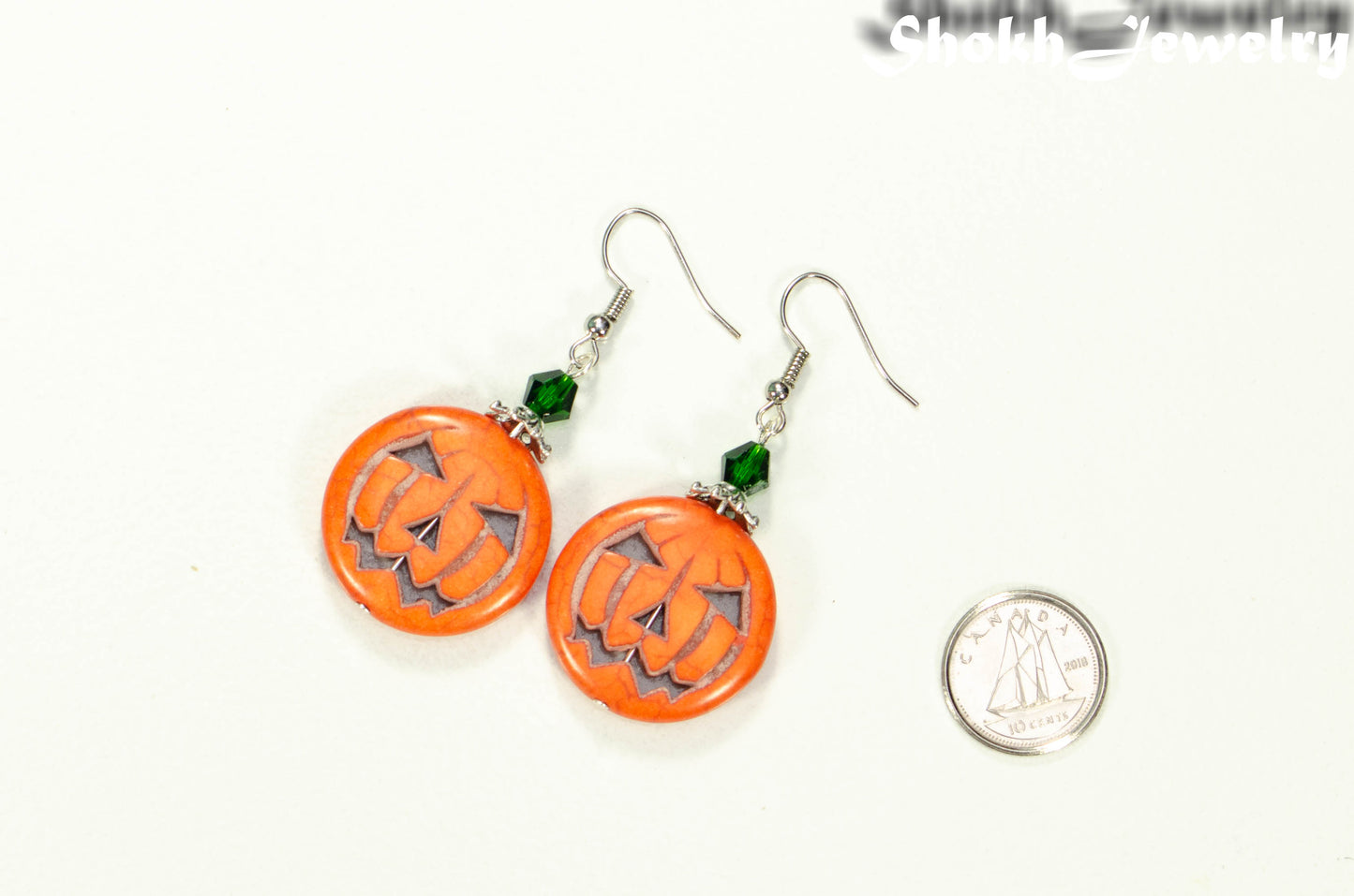 Spooky Halloween Pumpkin Earrings beside a dime.