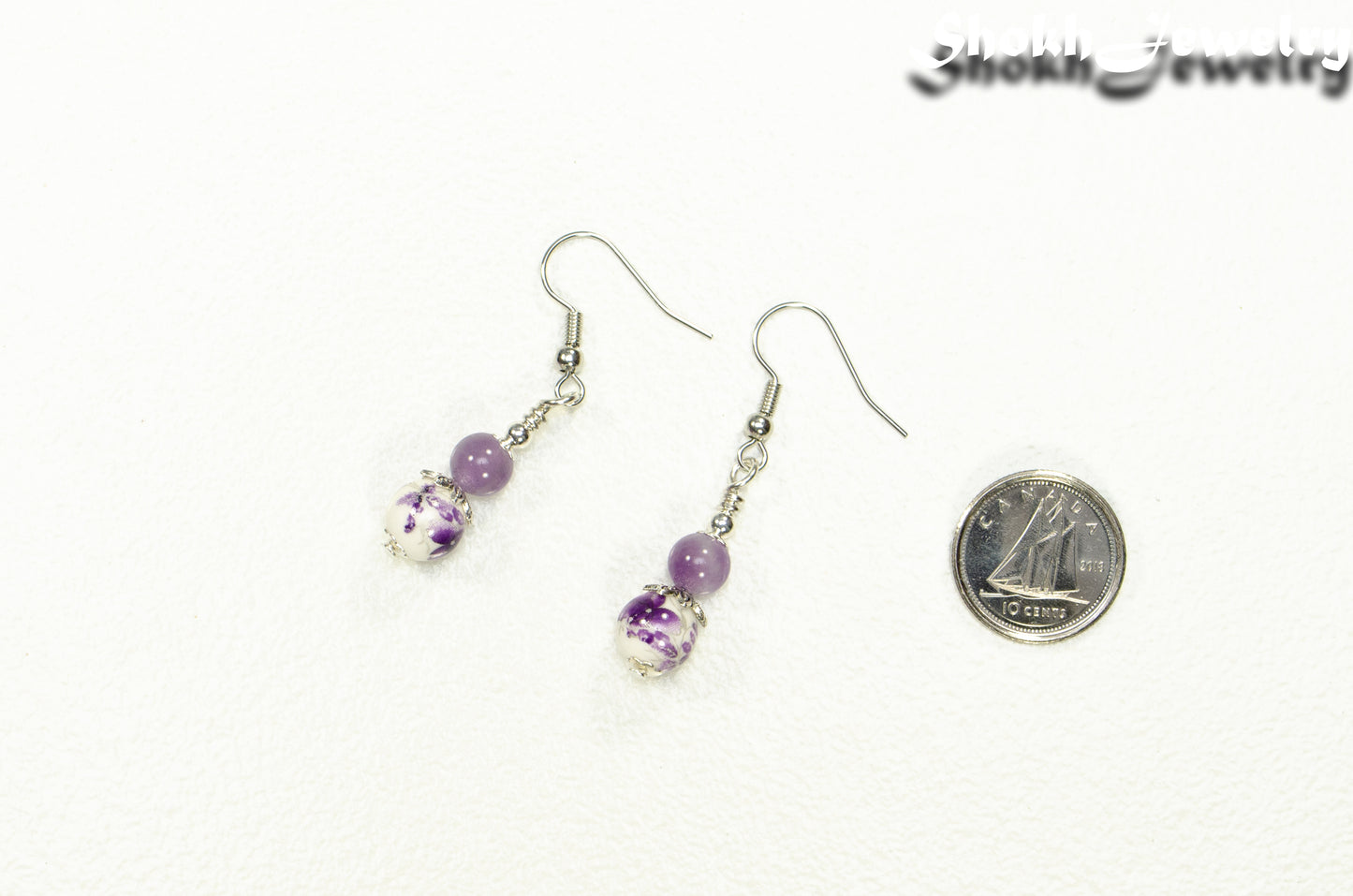 Small Floral Ceramic Bead and Amethyst Earrings beside a dime.