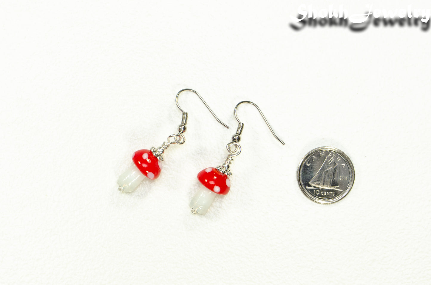 Tiny Red Mushroom Glass Bead Earrings beside a dime.