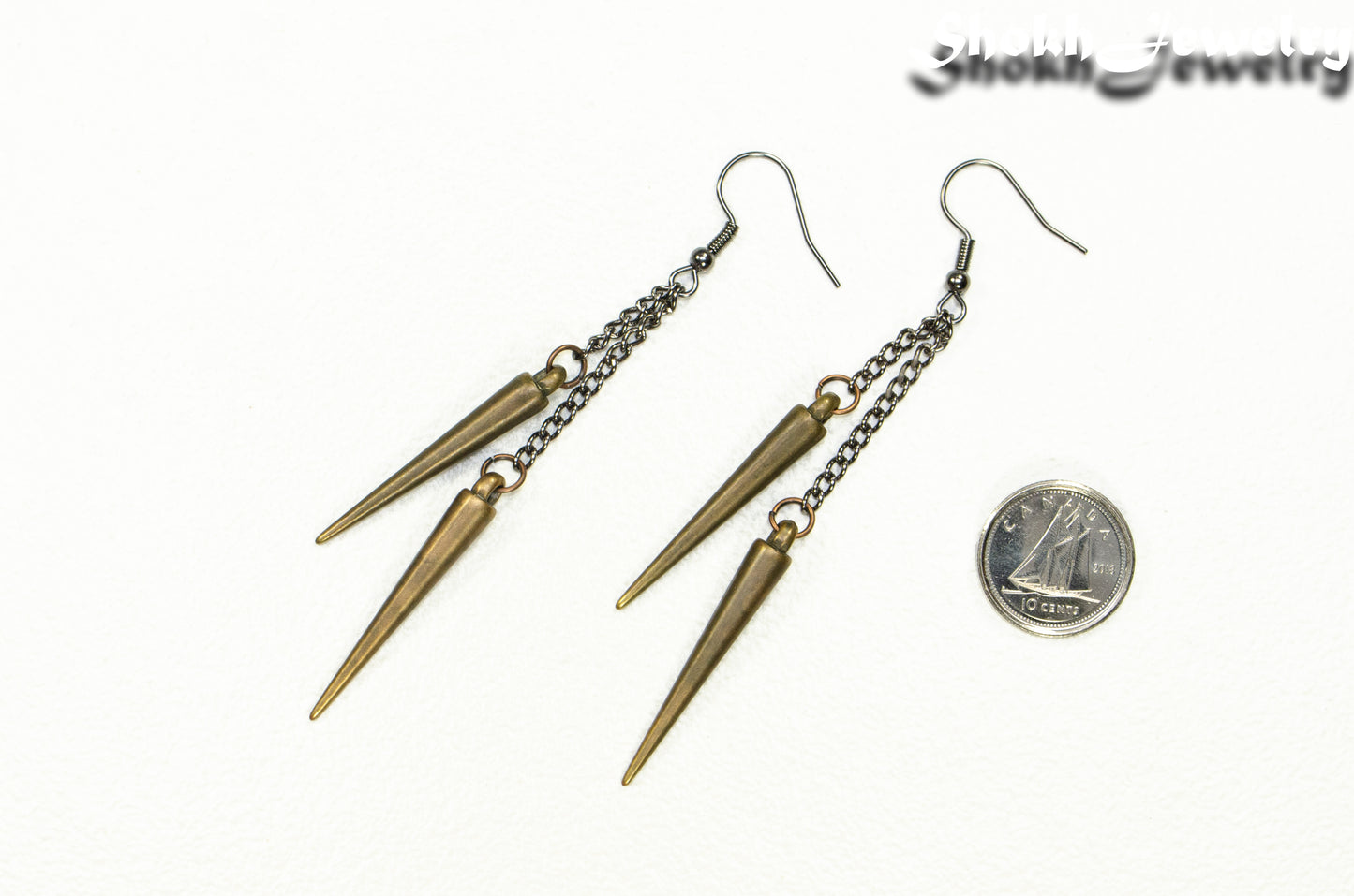 Long chain and antique bronze spike earrings beside a dime.