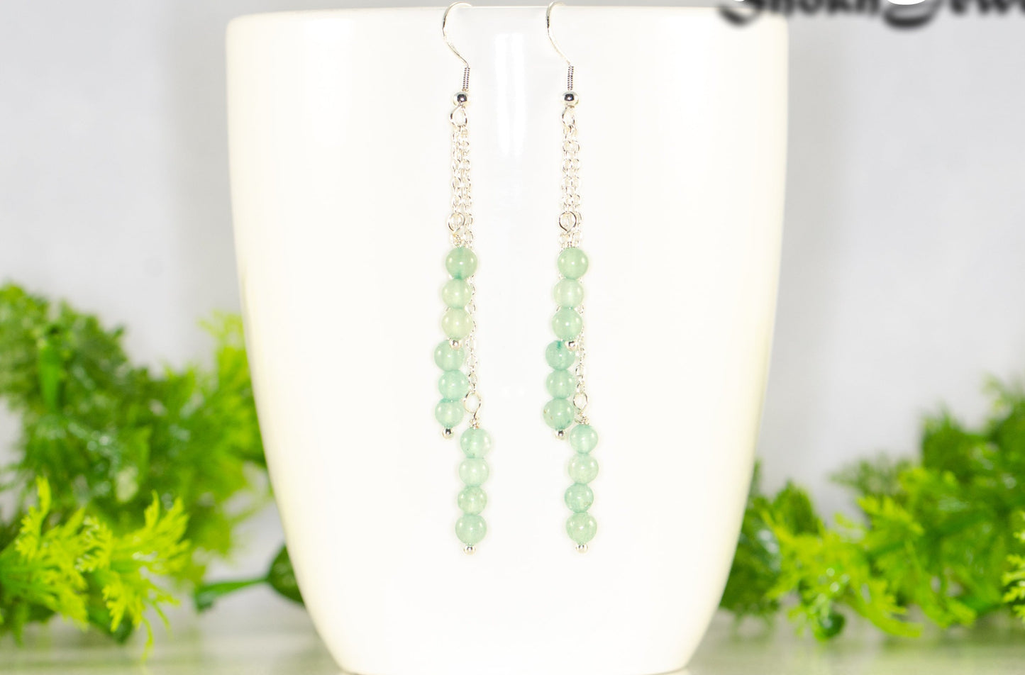 Silver Plated Chain and Green Aventurine Crystal Earrings displayed on a coffee mug.