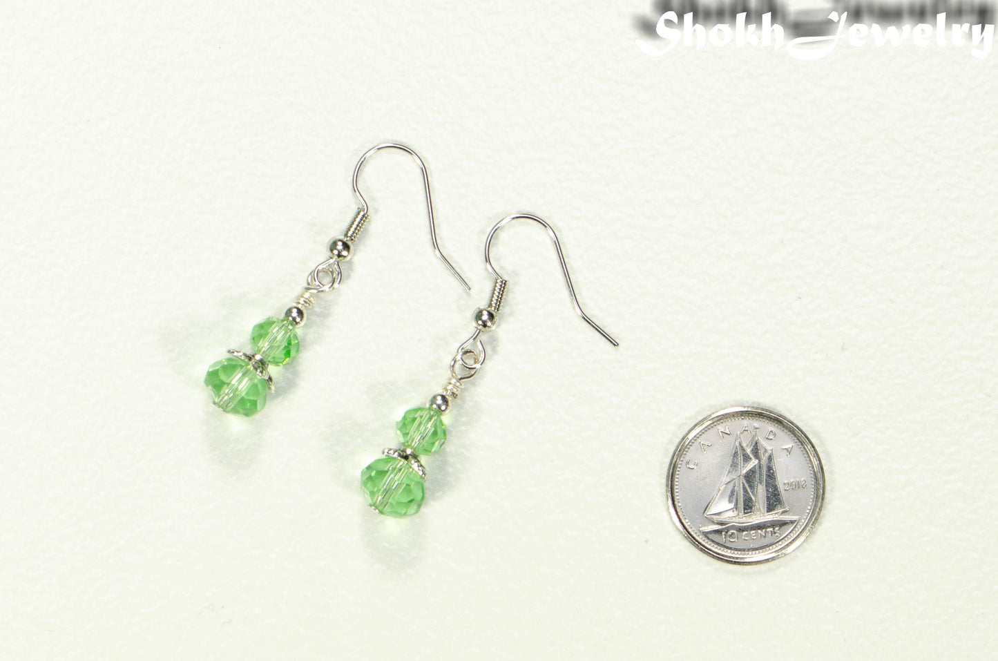 Small Light Green Glass Bead Dangle Earrings beside a dime.