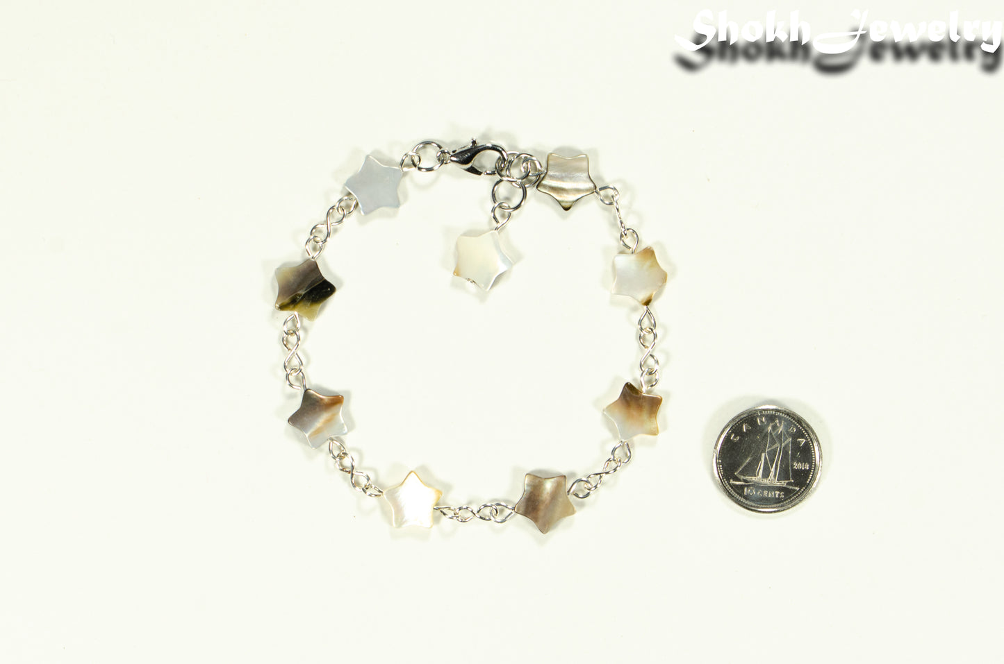 Natural Gray Seashell Star Link Bracelet beside a dime.