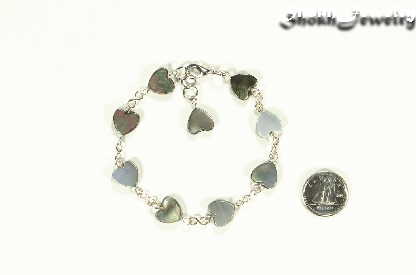 Grey Seashell Heart Link Bracelet beside a dime.