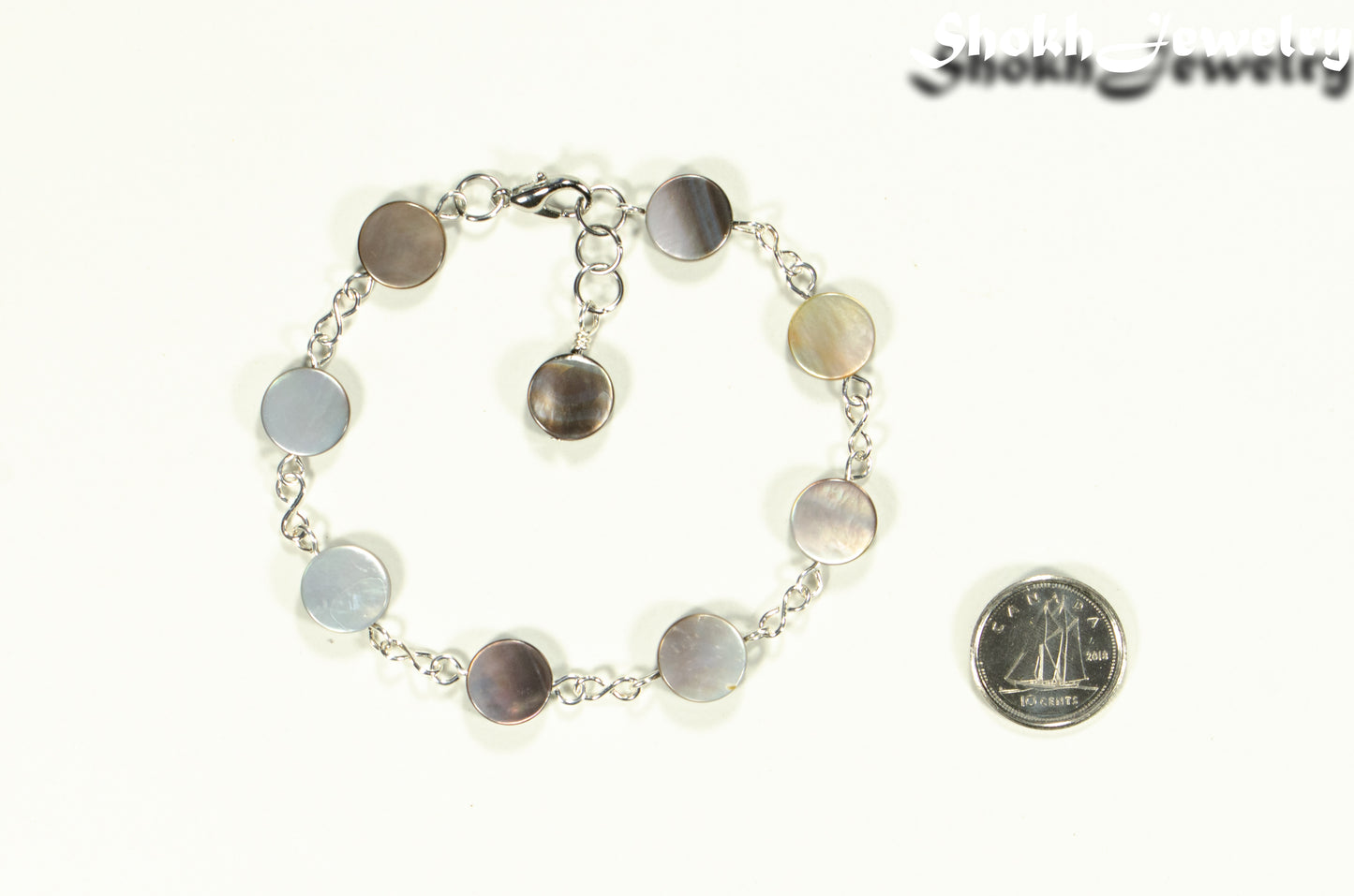 Grey Seashell Link Bracelet beside a dime.