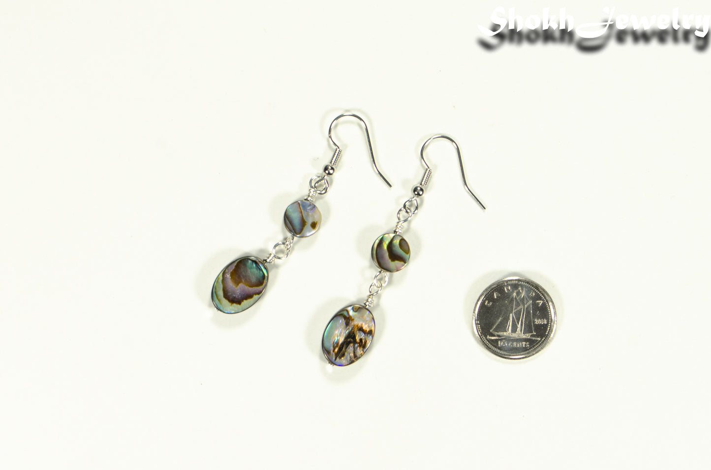 Elegant Long Oval Abalone Shell Earrings beside a dime.