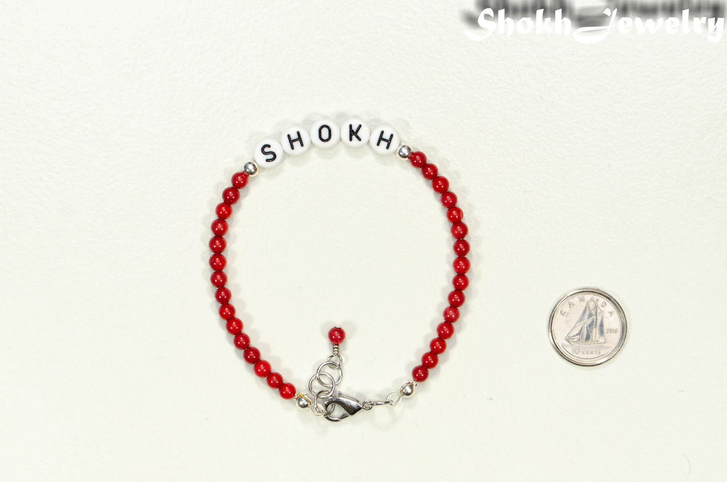 Personalized Natural Red Coral Bracelet with Clasp beside a dime.